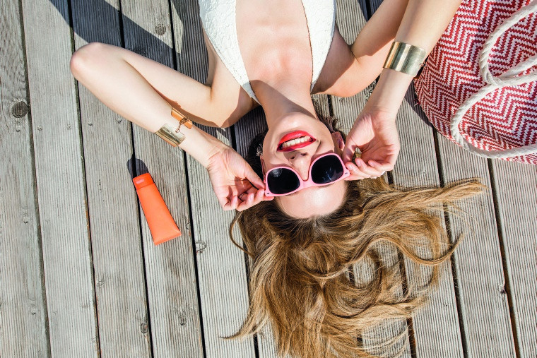 Frau mit Sonnenbrille und Sonnencreme