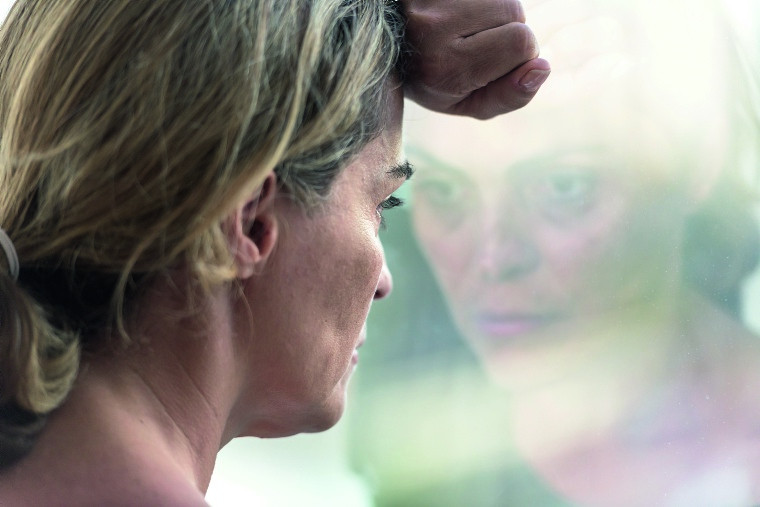 Traurige Frau schaut aus dem Fenster.