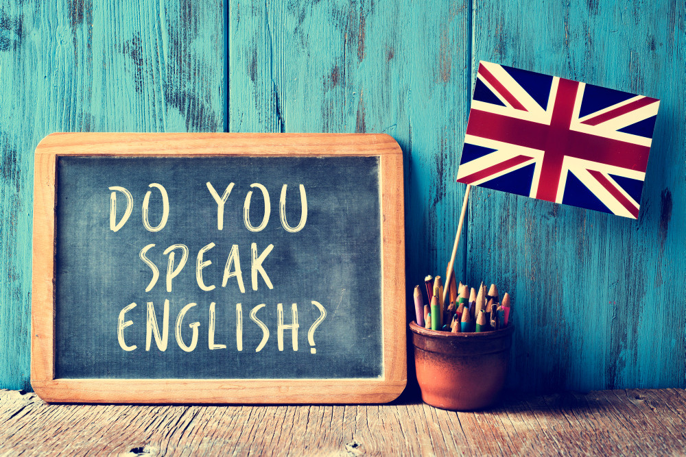 "Do you speak English" auf einer Schiefertafel neben einer britischen Flagge.