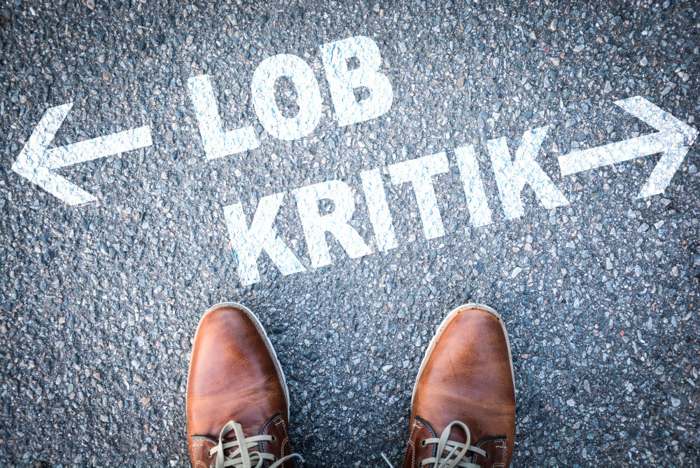 Lob und Kritik auf dem Boden neben zwei Herrenschuhen Lob und Kritik auf dem Boden neben zwei Herrenschuhen
