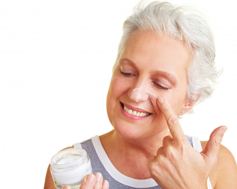 Ältere Frau nutzt Hautcreme.