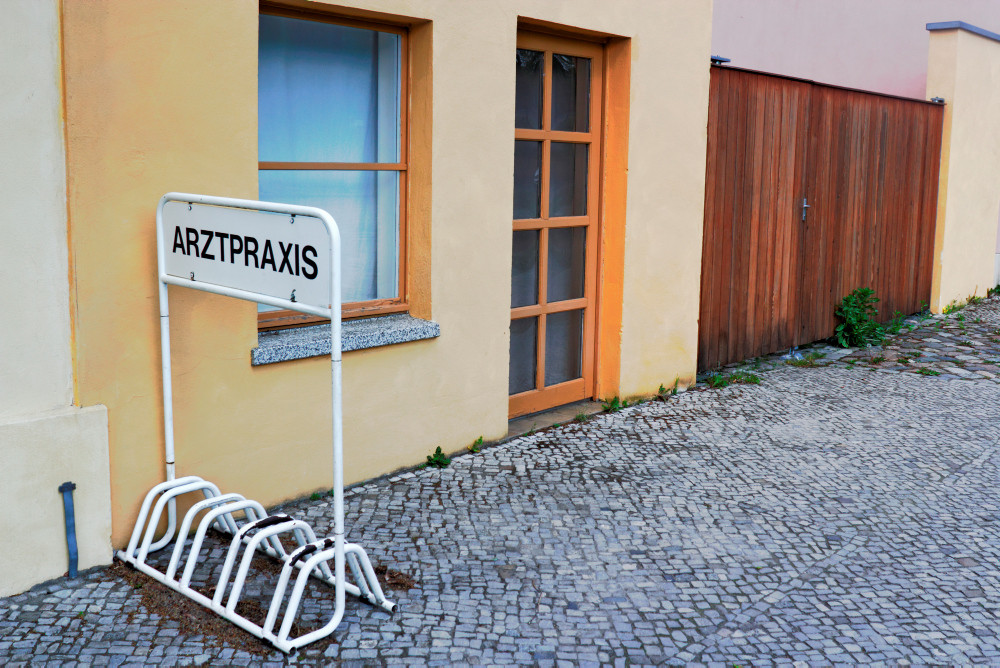 Verlassenes Gebäude mit einem Fahrradständer mit Beschriftung Arztpraxis davor Verlassenes Gebäude mit einem Fahrradständer mit Beschriftung Arztpraxis davor