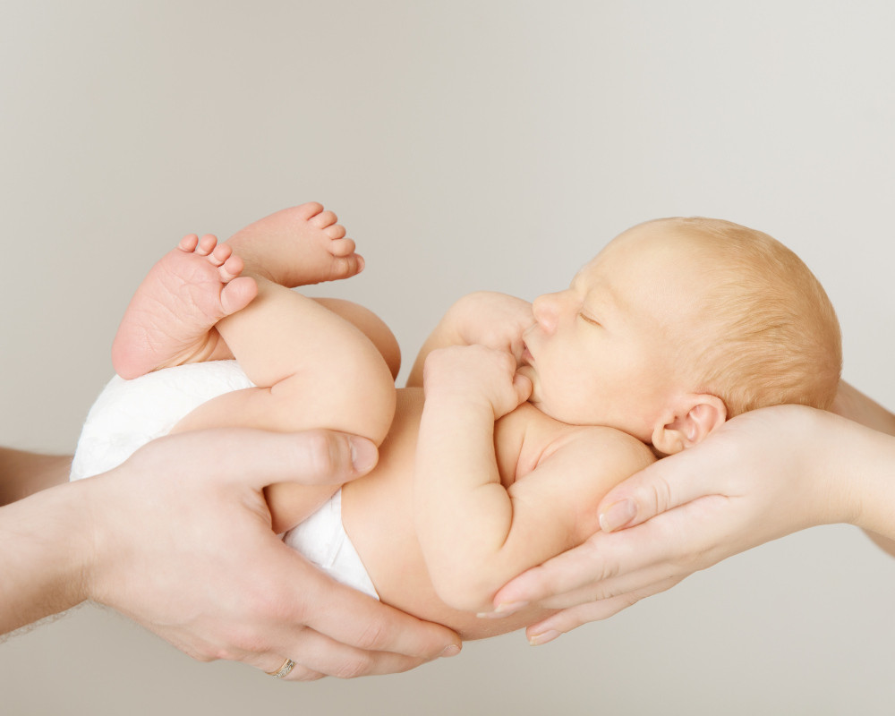 Neugeborenes schläft in den Händen seiner Eltern