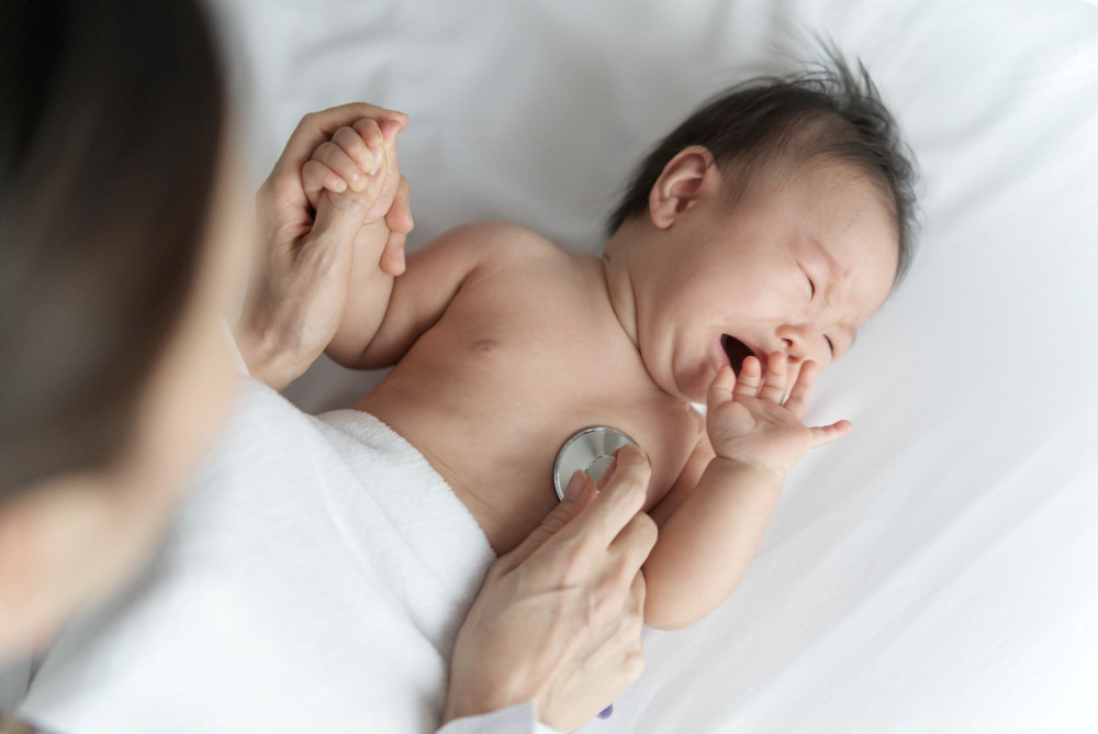 Arzt hört Herzschlag mit Stethoskop bei einem Baby ab