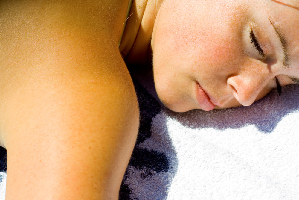 Gesicht und Schulter einer jungen Frau beim Sonnenbaden