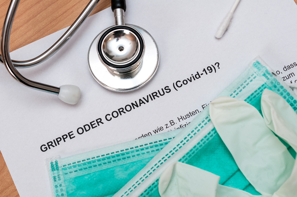 Paper „Grippe oder Corona“ mit Stethoskop und Einmalmasken und Einmalhandschuhen