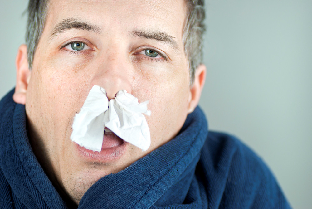 Kranker Mann mit Taschentuch in der Nase