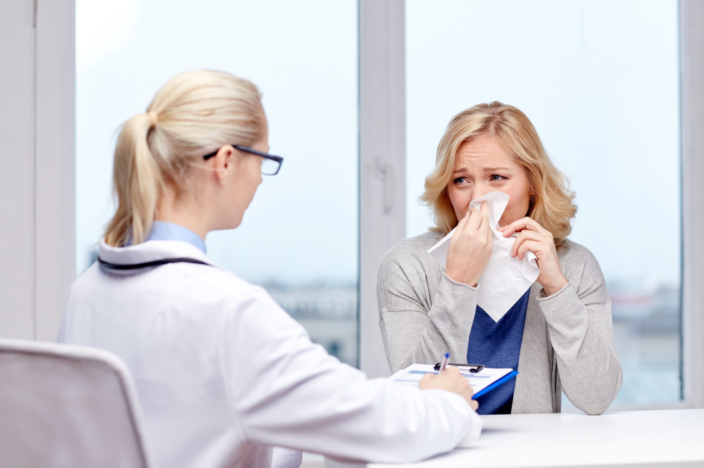 Frau mit Grippe im Gespräch mit einer Ärztin