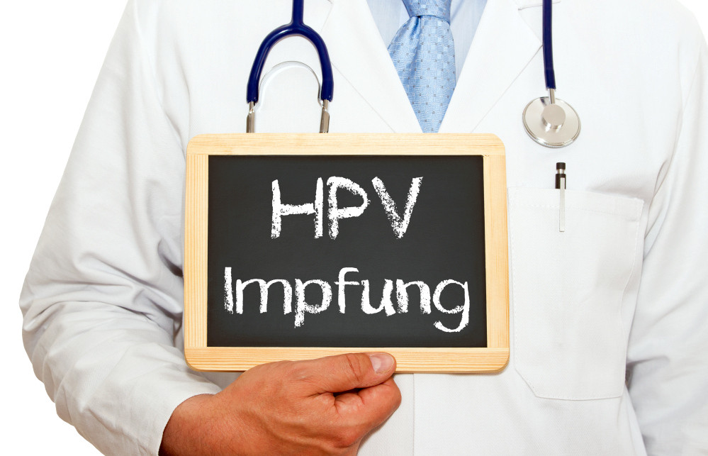 Arzt hält Tafel mit Aufschrift HPV Impfung