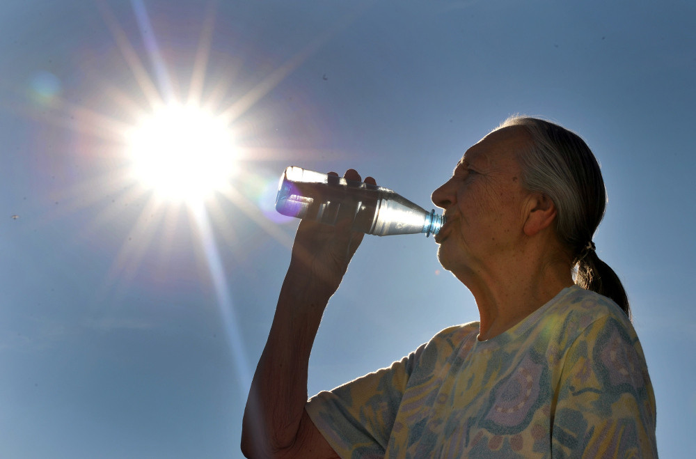 Seniorin trinkt Mineralwasser an einem heißen Tag