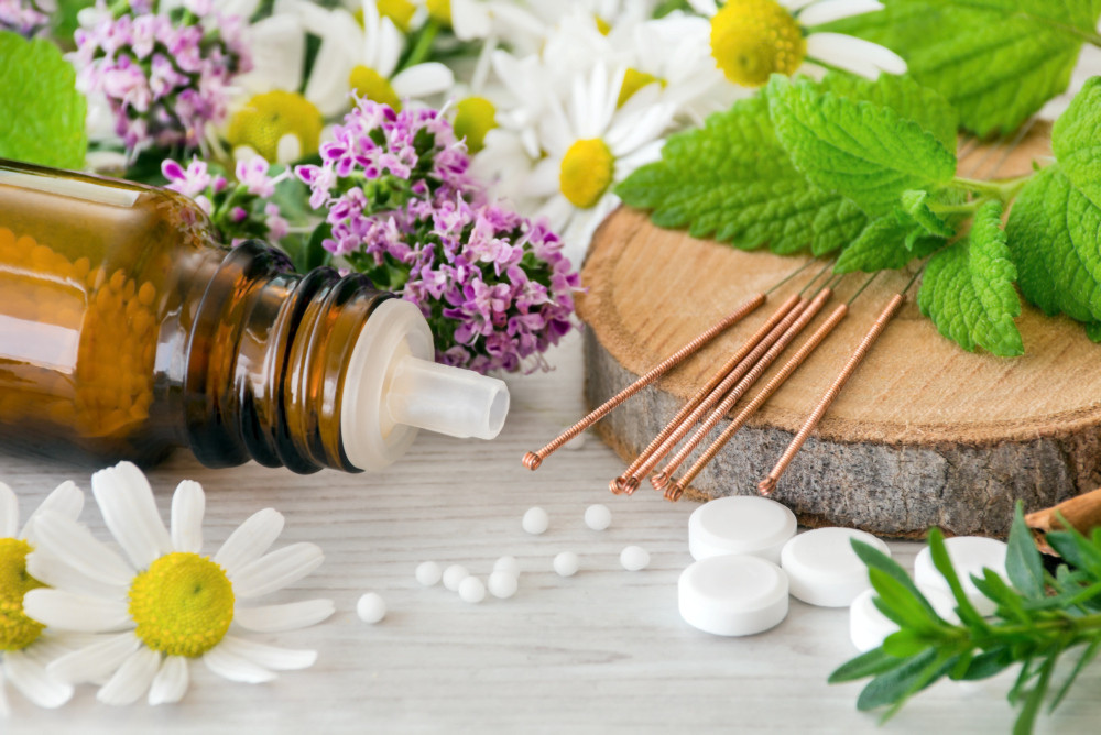 Umgekipptes Globulifläschchen und Tabletten umgeben von Pflanzen