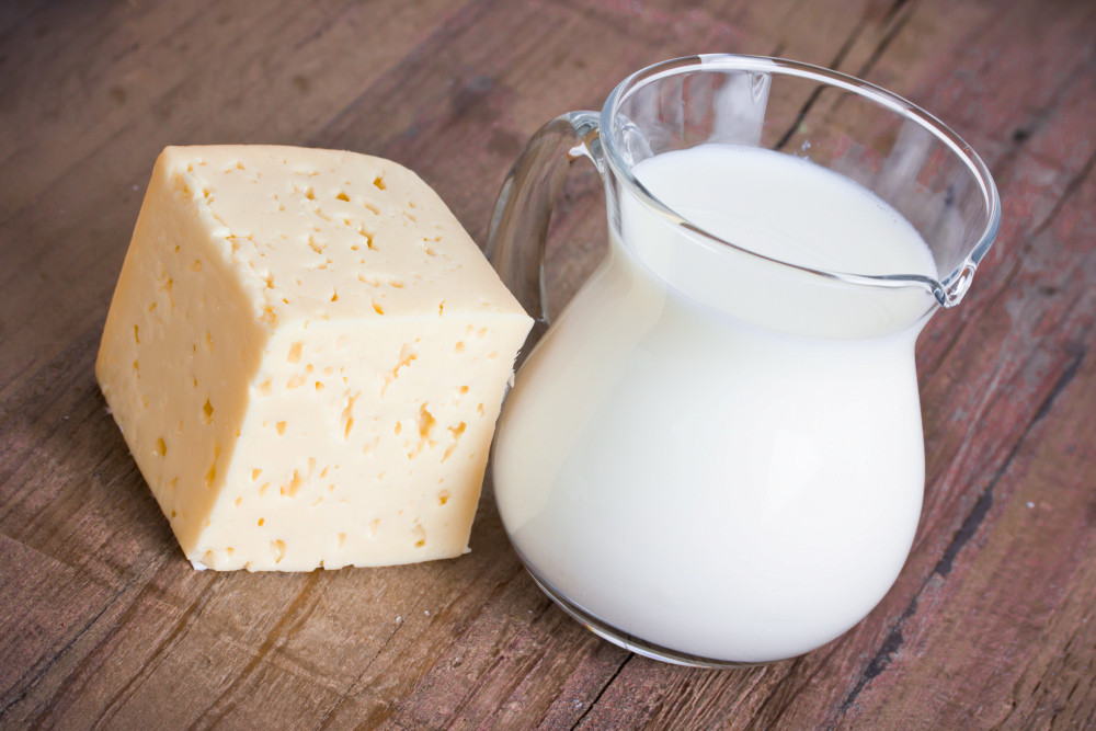 Käse und ein Krug Milch auf einem Holztisch