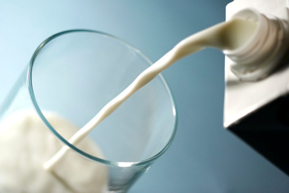 Milch aus einem Tetra Pak wird in ein Glas gegossen