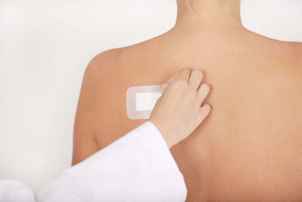 Arzt klebt einem Patienten ein Pflaster auf den Rücken Arzt klebt einem Patienten ein Pflaster auf den Rücken