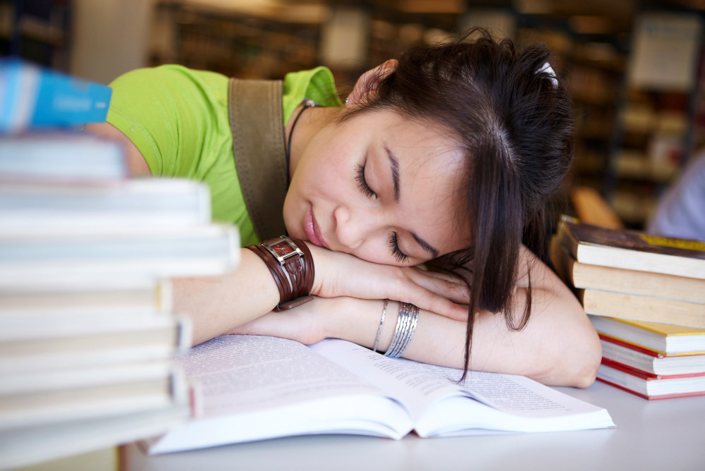 Schülerin schläft über ihren Büchern ein