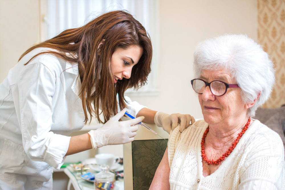 Seniorin erhält Impfung durch Medizinische Fachkraft