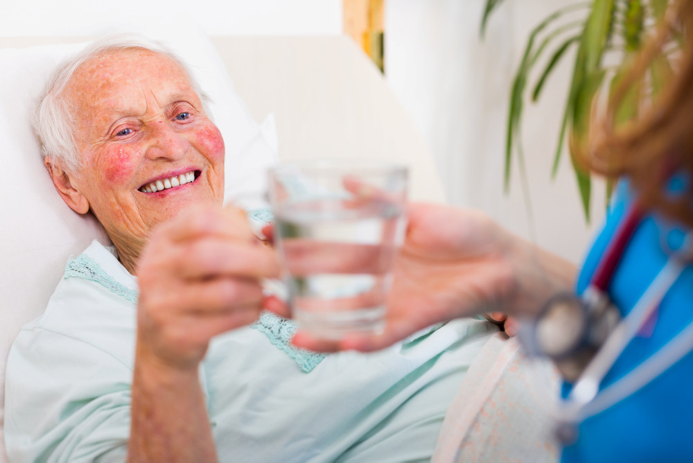 Seniorin erhält von einer Pflegekraft ein Glas Wasser Seniorin erhält von einer Pflegekraft ein Glas Wasser