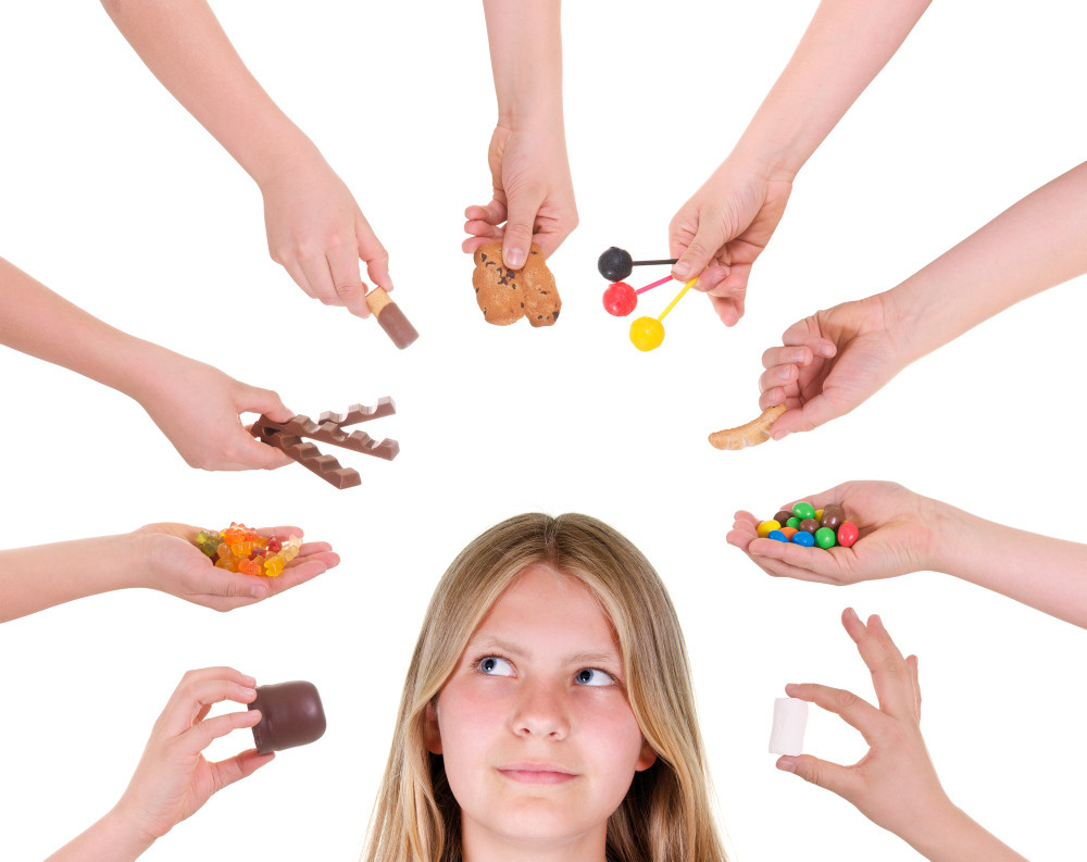Viele Hände mit Süßigkeiten, in der Mitte ein Mädchen