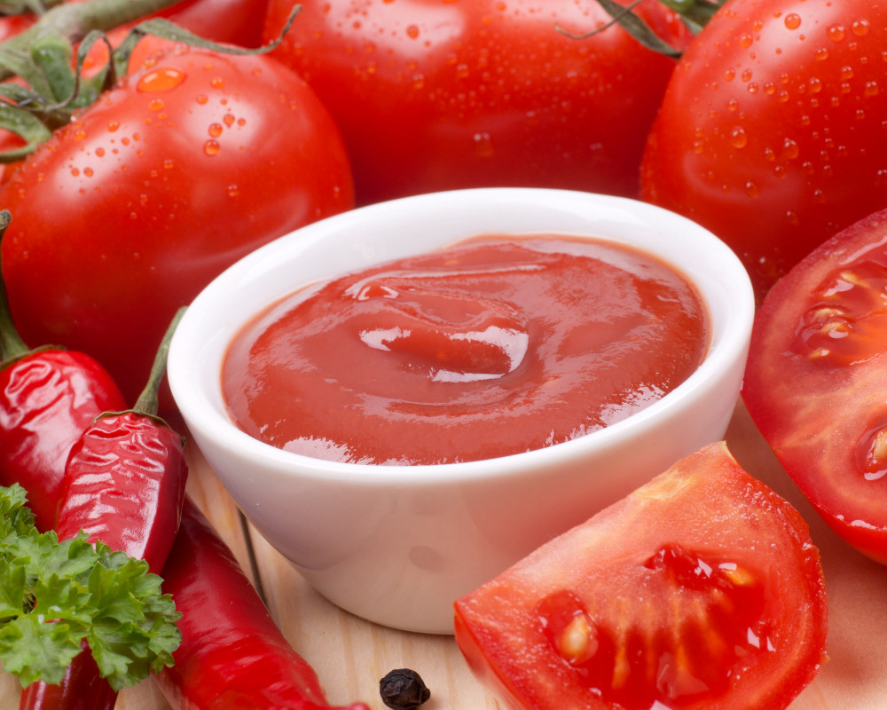 rohe, rote Tomaten und Chilischoten, gruppiert um eine kleine Schale Ketchup. rohe, rote Tomaten und Chilischoten, gruppiert um eine kleine Schale Ketchup.