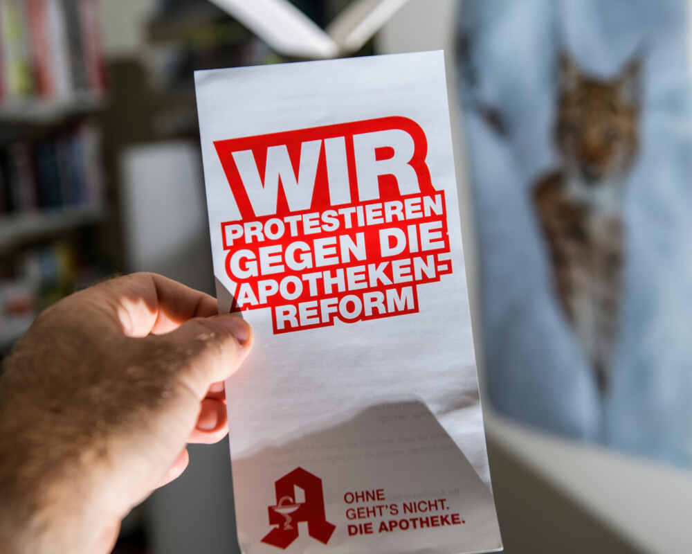 Hand hält Kassenbon mit Aufschrift „Wir protestieren gegen die Apothekenreform“.