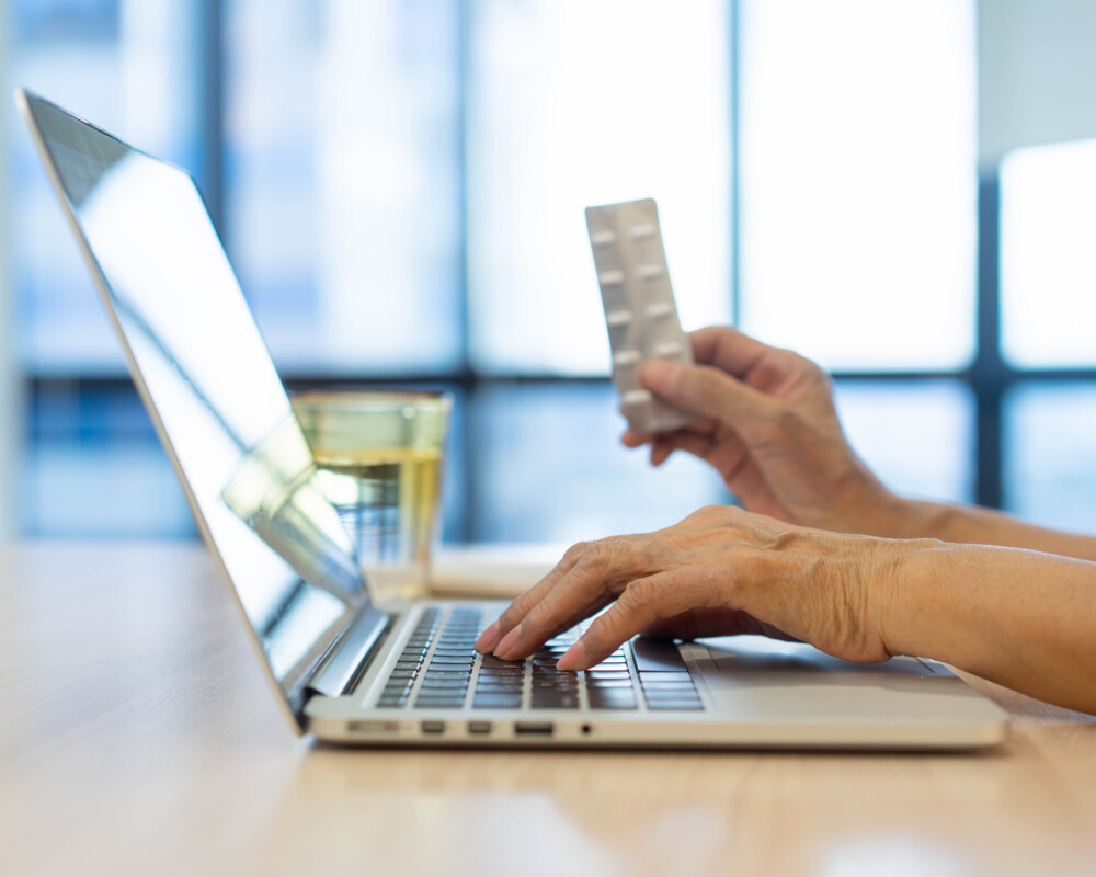 Laptop, Person mit Tabletten in der Hand