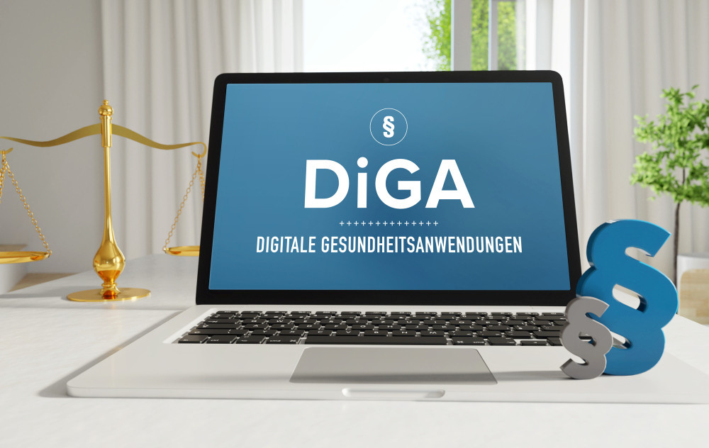 Aufgeklappter Laptop mit Anzeige „DIGA – Digitale Gesundheitsanwendungen“, Paragrafen, goldene Waage