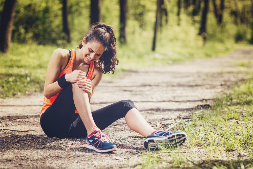 Sportlerin hält sich das verletzte Knie