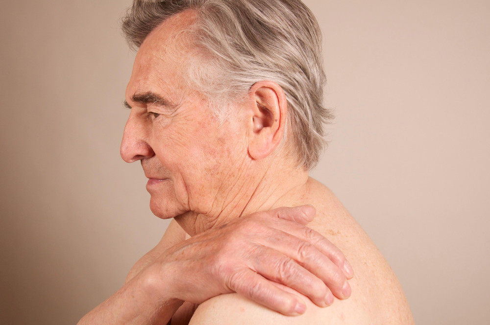 älterer Mann greift sich an Schulter