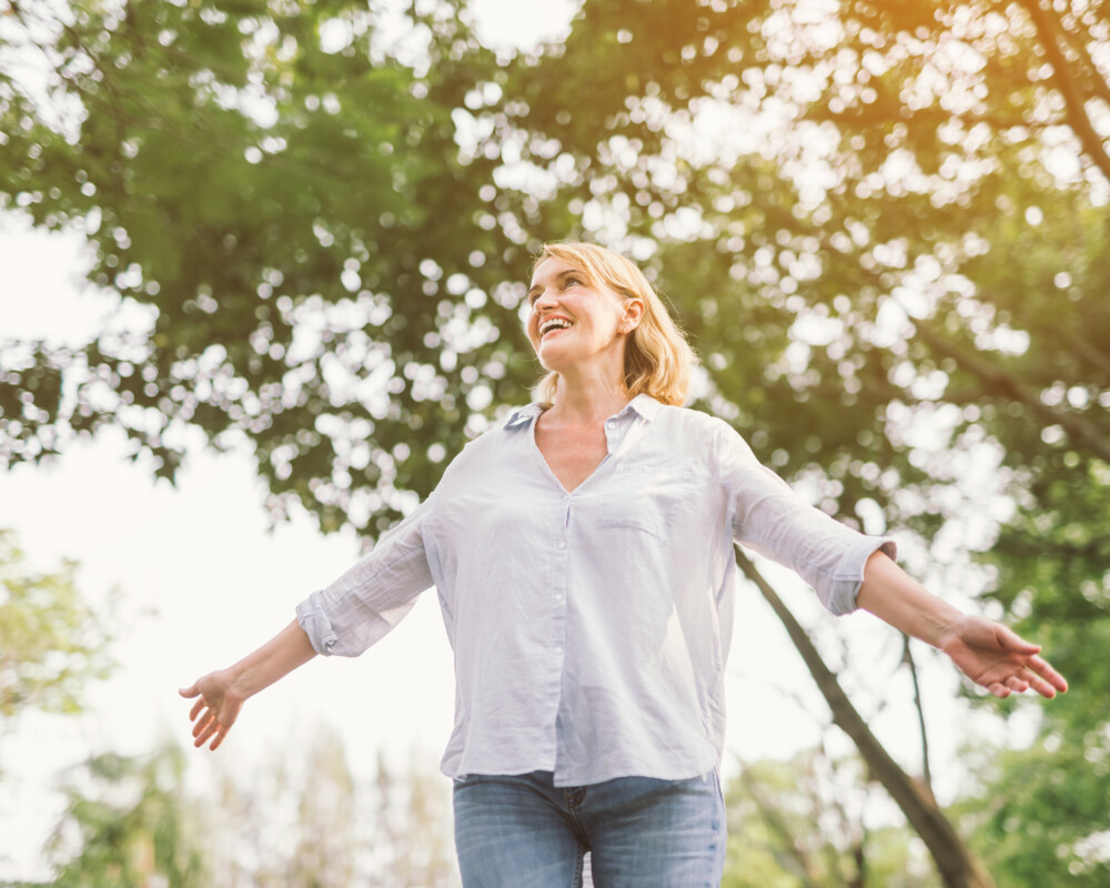 Frau mit offenen Armen in der Natur