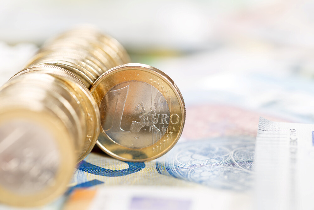 Eine Reihe von Euromünzen auf einem 20-Euro-Schein. Ein Münze schert aus der Reihe aus Eine Reihe von Euromünzen auf einem 20-Euro-Schein. Ein Münze schert aus der Reihe aus