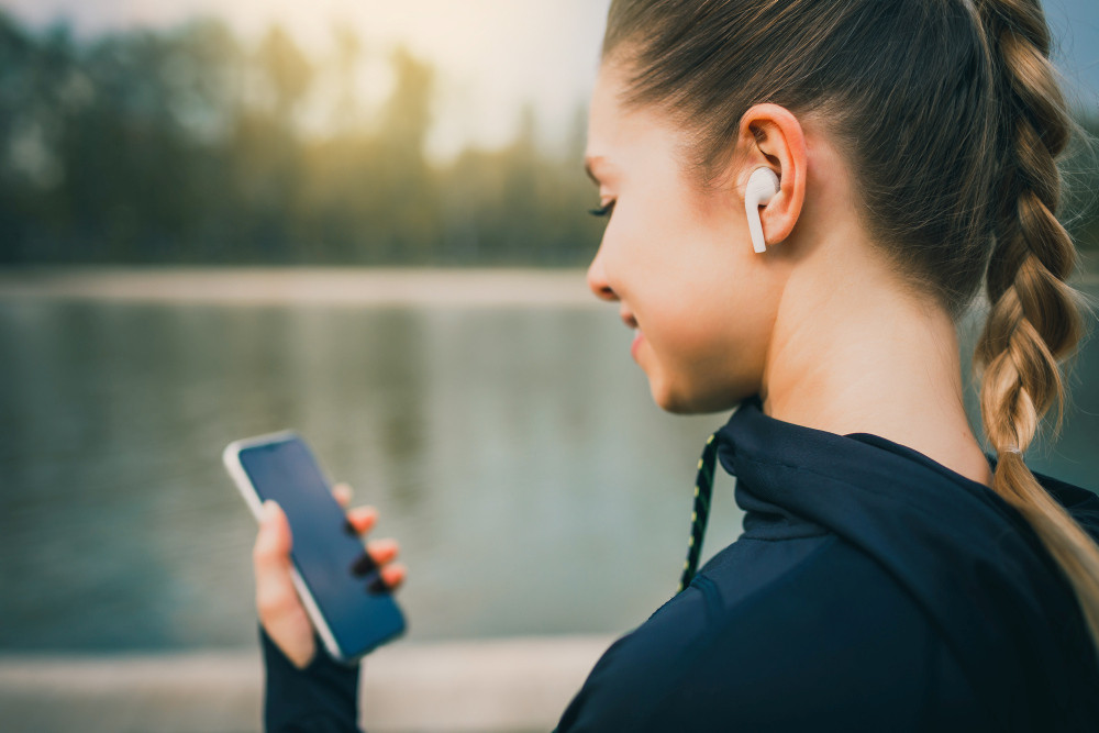 Lächelnde Frau mit Handy in der Hand vor einem See