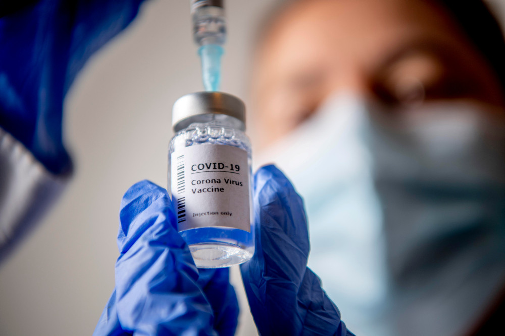 Flasche mit Covid-19-Impfstoff, aus der eine Impfdosis aufgezogen wird. Flasche mit Covid-19-Impfstoff, aus der eine Impfdosis aufgezogen wird.