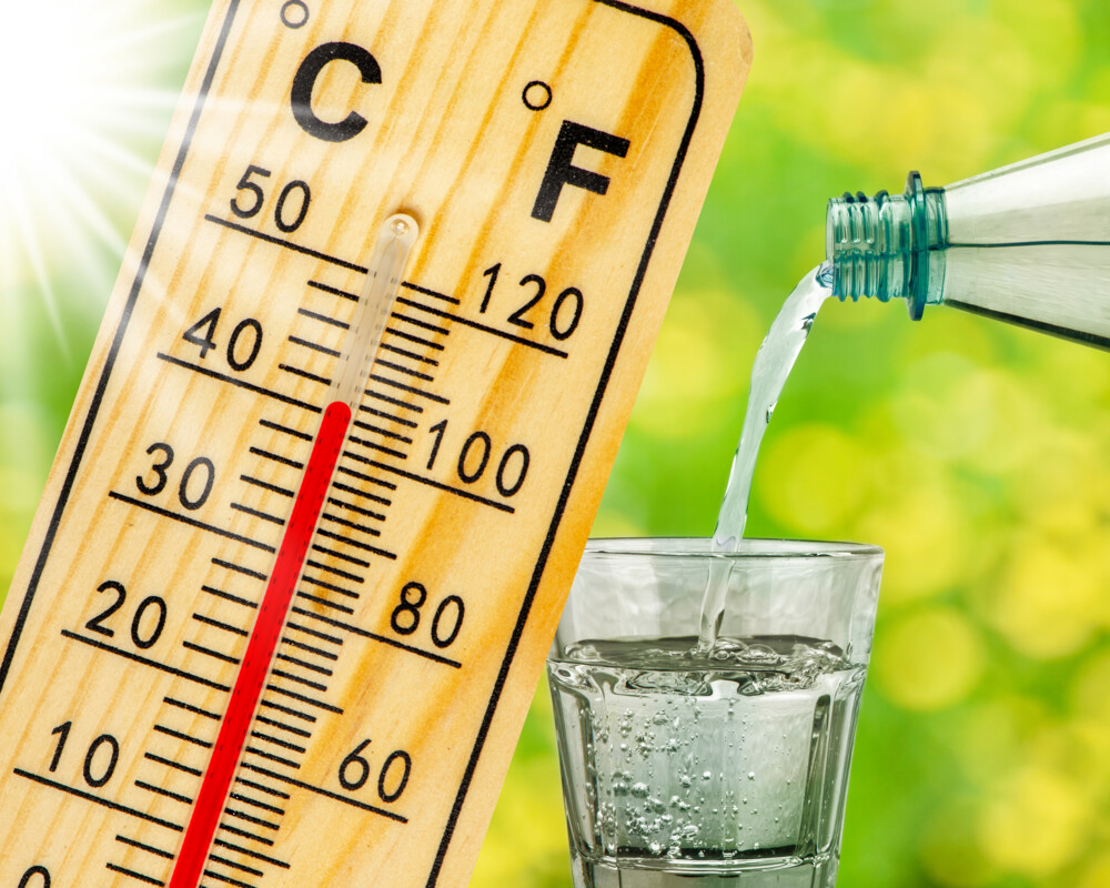 Holzthermometer zeigt über 40 Grad Celsius an, daneben ein Glas, in das aus einer Flasche Wasser eingegossen wird. Holzthermometer zeigt über 40 Grad Celsius an, daneben ein Glas, in das aus einer Flasche Wasser eingegossen wird.
