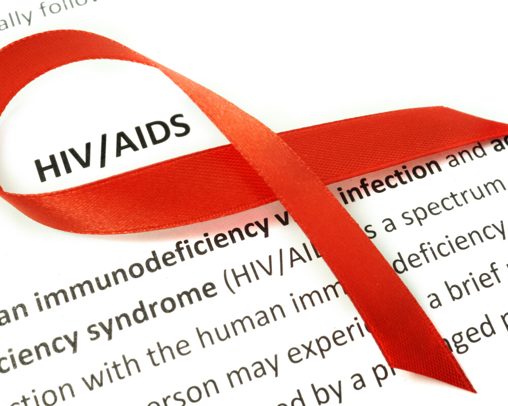 Rote HIV/AIDS-Schleife auf einem Papier, das die Krankheit definiert.