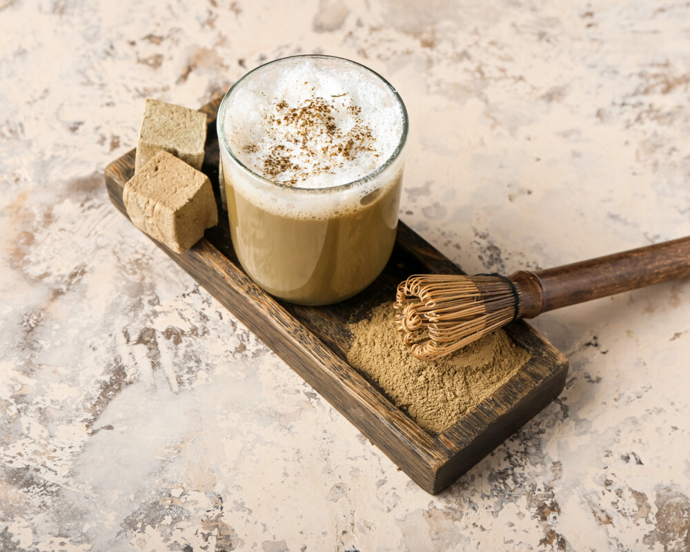 Glas mit Hojicha-Tee, Chasen, Pulver und zwei Marshomallows