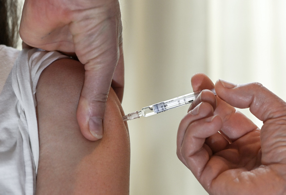 Spritze mit Impfstoff wird in den Oberarm gestochen