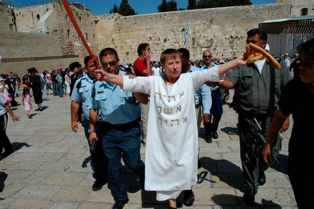 weiß gewandete Frau umgeben von Polizisten in Jerusalem