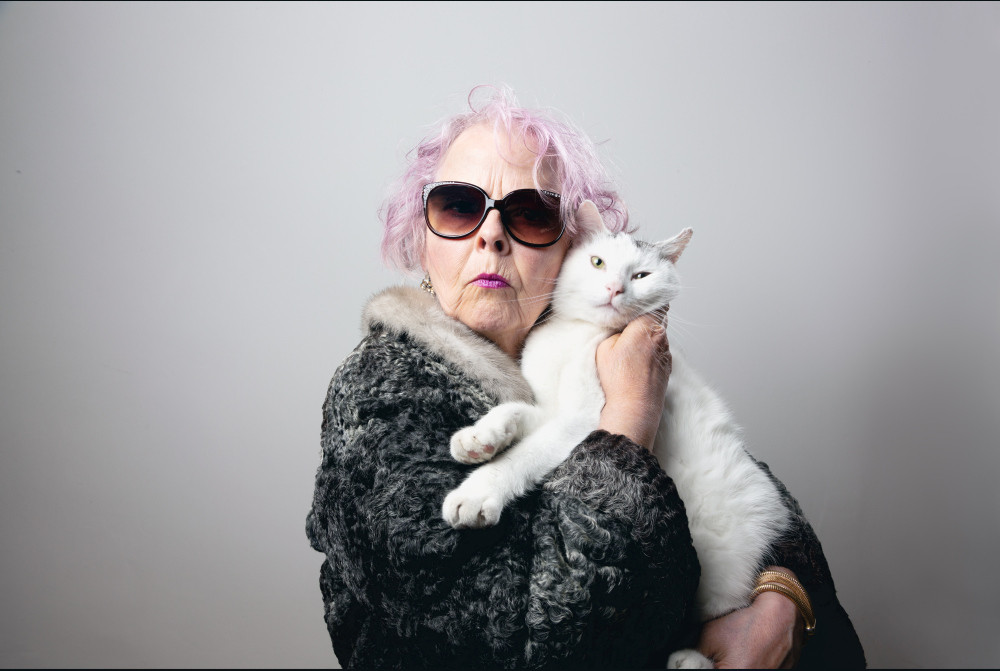 Extravagante Seniorin mit Katze auf dem Arm
