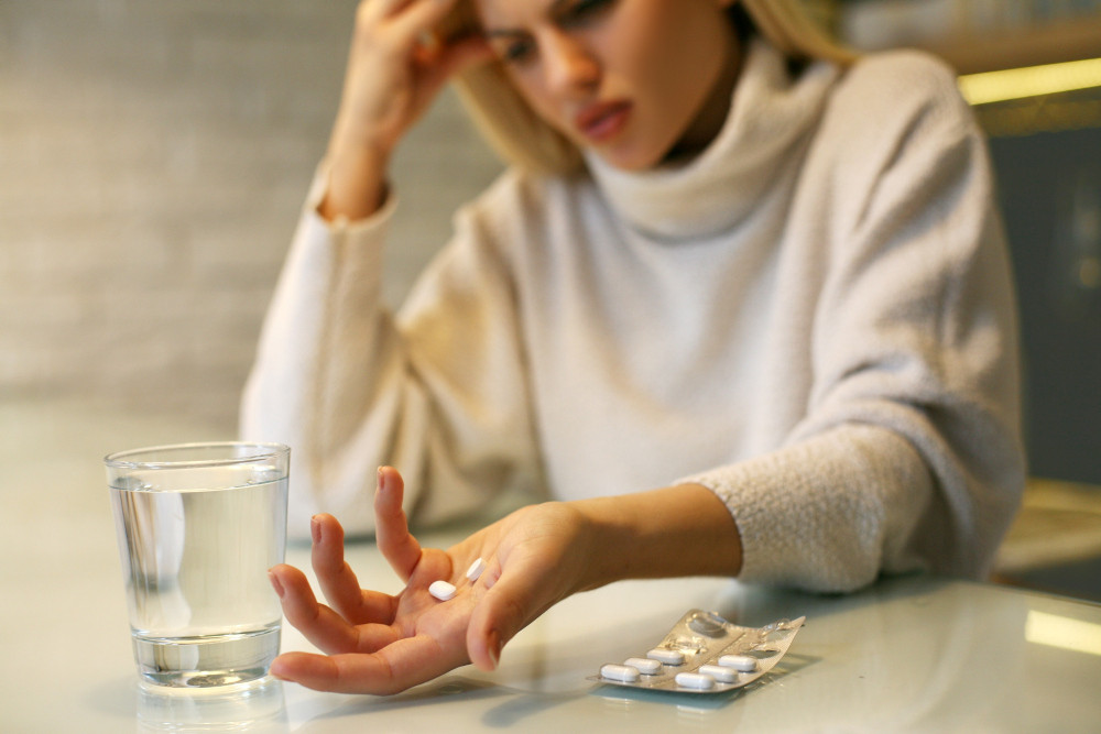Frau mit Kopfschmerzen möchte Tablette einnehmen