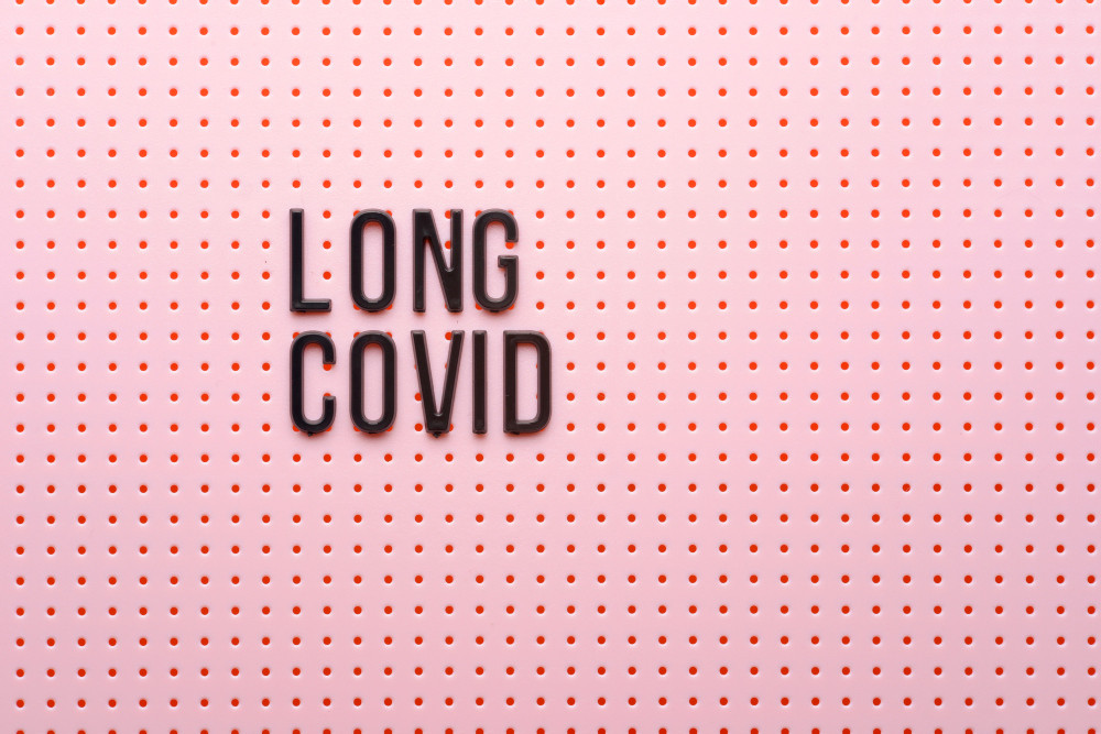 Rosafarbener Hintergrund mit Löchern und Aufschrift „LONG COVID“