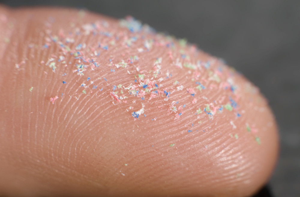 Mikroplastikpartikel auf einem Finger in Großaufnahme