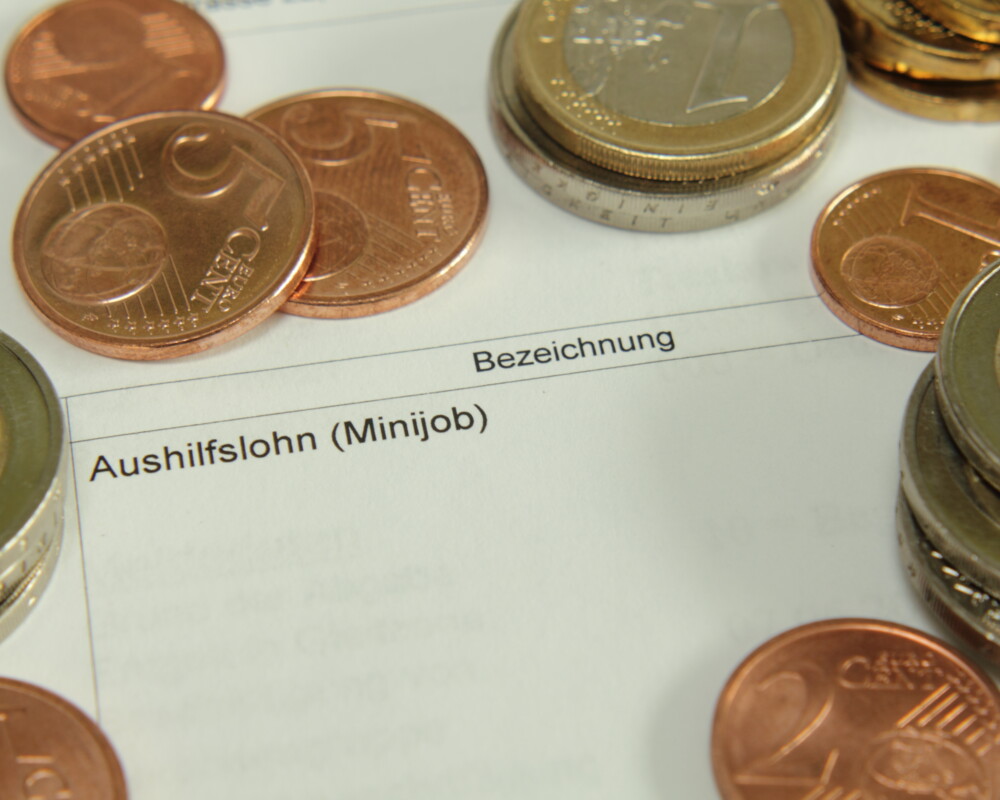 Euro- und Centmünzen auf einem Ausdruck mit Gehaltsabrechnung (Aushilfslohn (Minijob)).