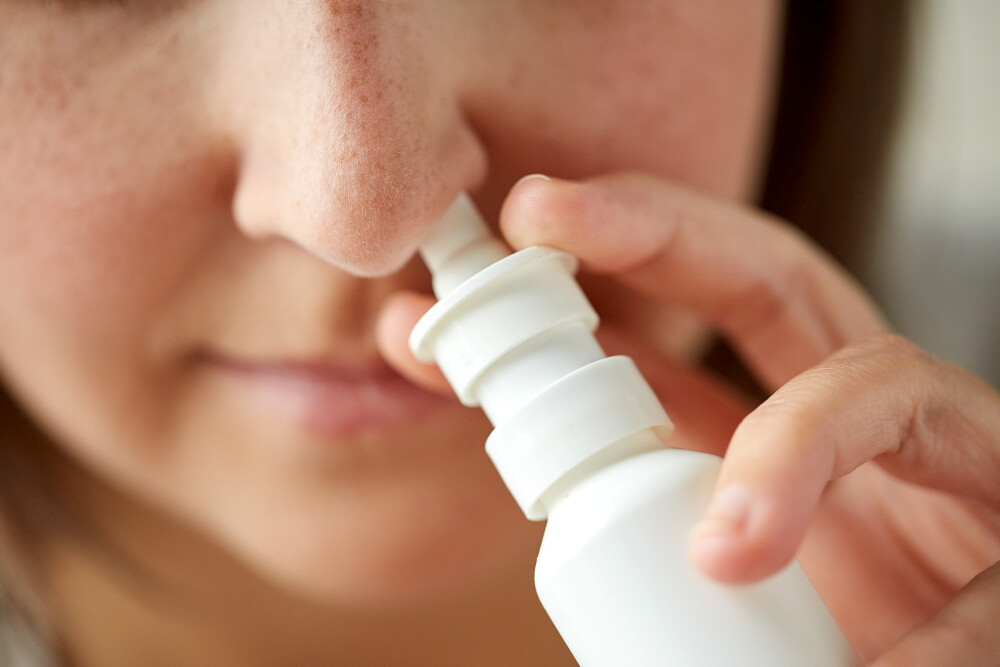 Frau nutzt Nasenspray Frau nutzt Nasenspray