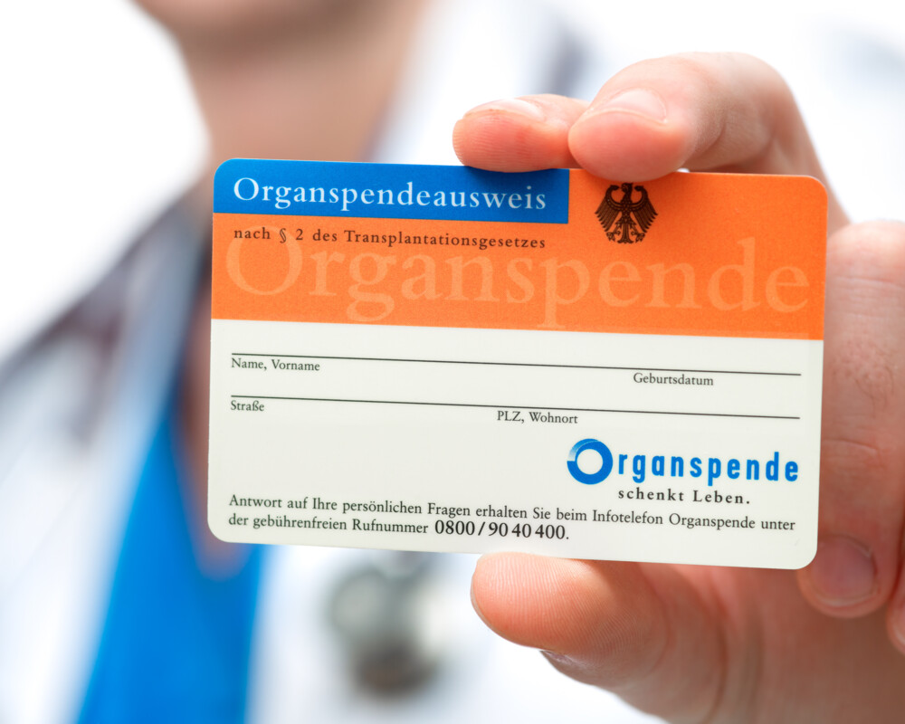 Arzt hält einen Organspendeausweis in die Kamera# Arzt hält einen Organspendeausweis in die Kamera#