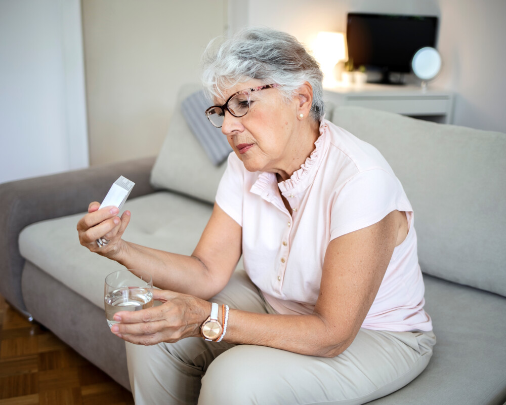 Frau mit Medikament und Wasserglas