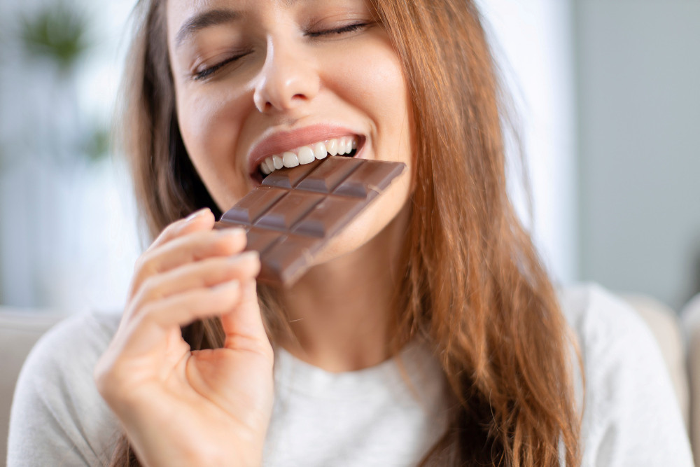Junge Frau beißt in eine Schokoladentafel