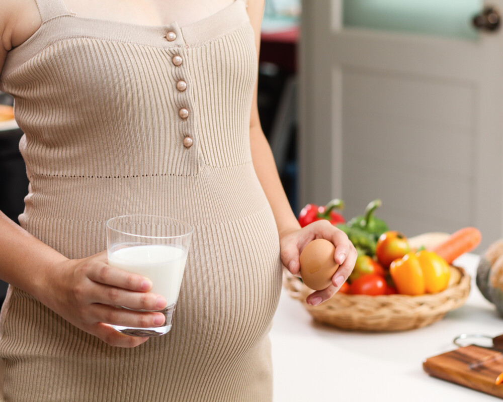 Schwanger mit Glas Milch und einem Ei in der Hand