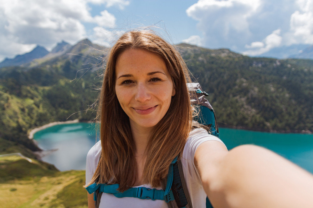 Frau macht Selfie vor Bergpanorama