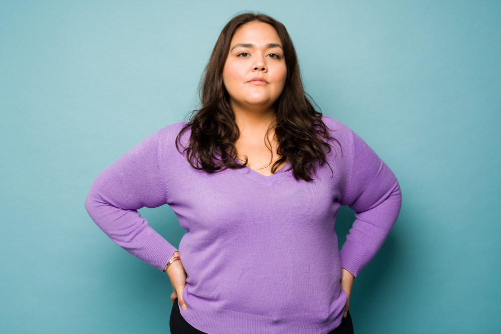 Junge, übergewichtige Frau in lilafarbenem Pullover