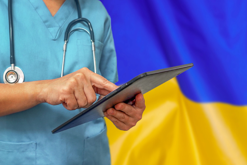 Arzt mit Tablet vor der ukrainischen Flagge